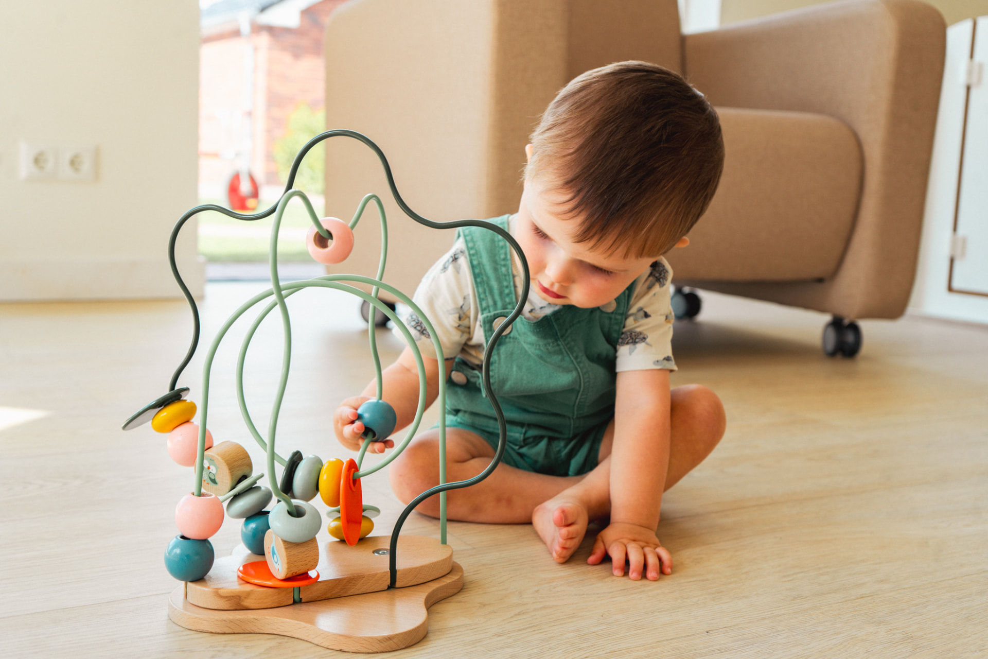 Baby speelt op de vloer met een houten kralenspiraal