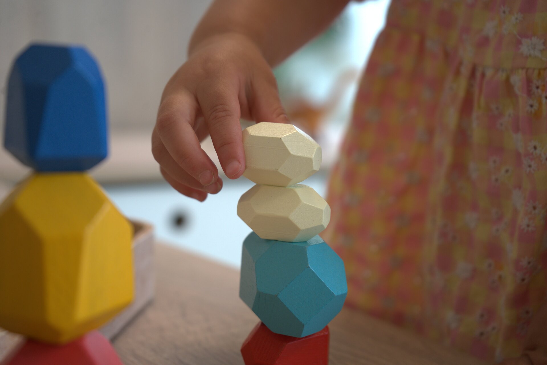 Kinderhand stapelt gekleurde houten stenen