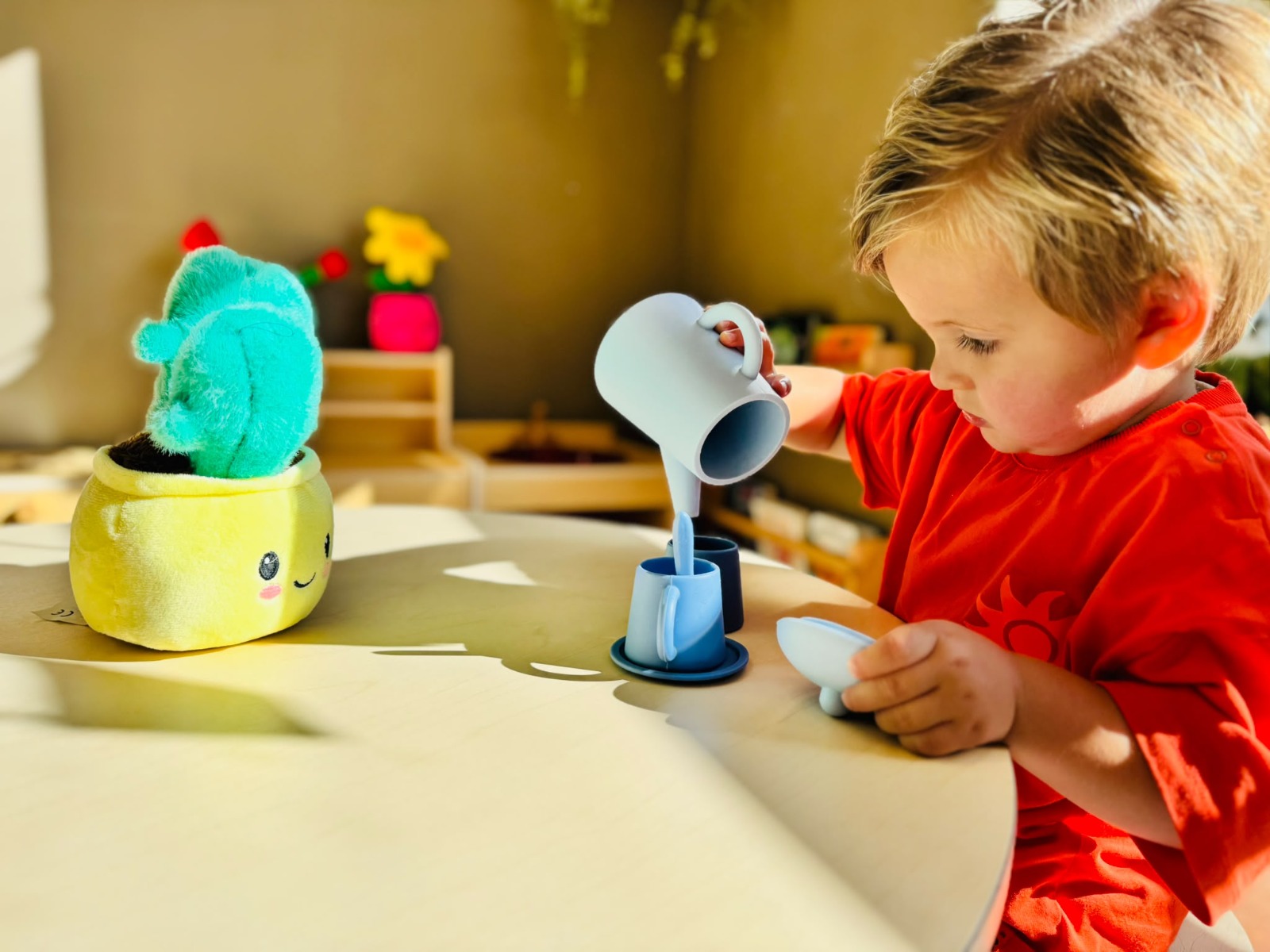 Peuter die met een blauw theeserviesje speelt aan een tafel in de groep