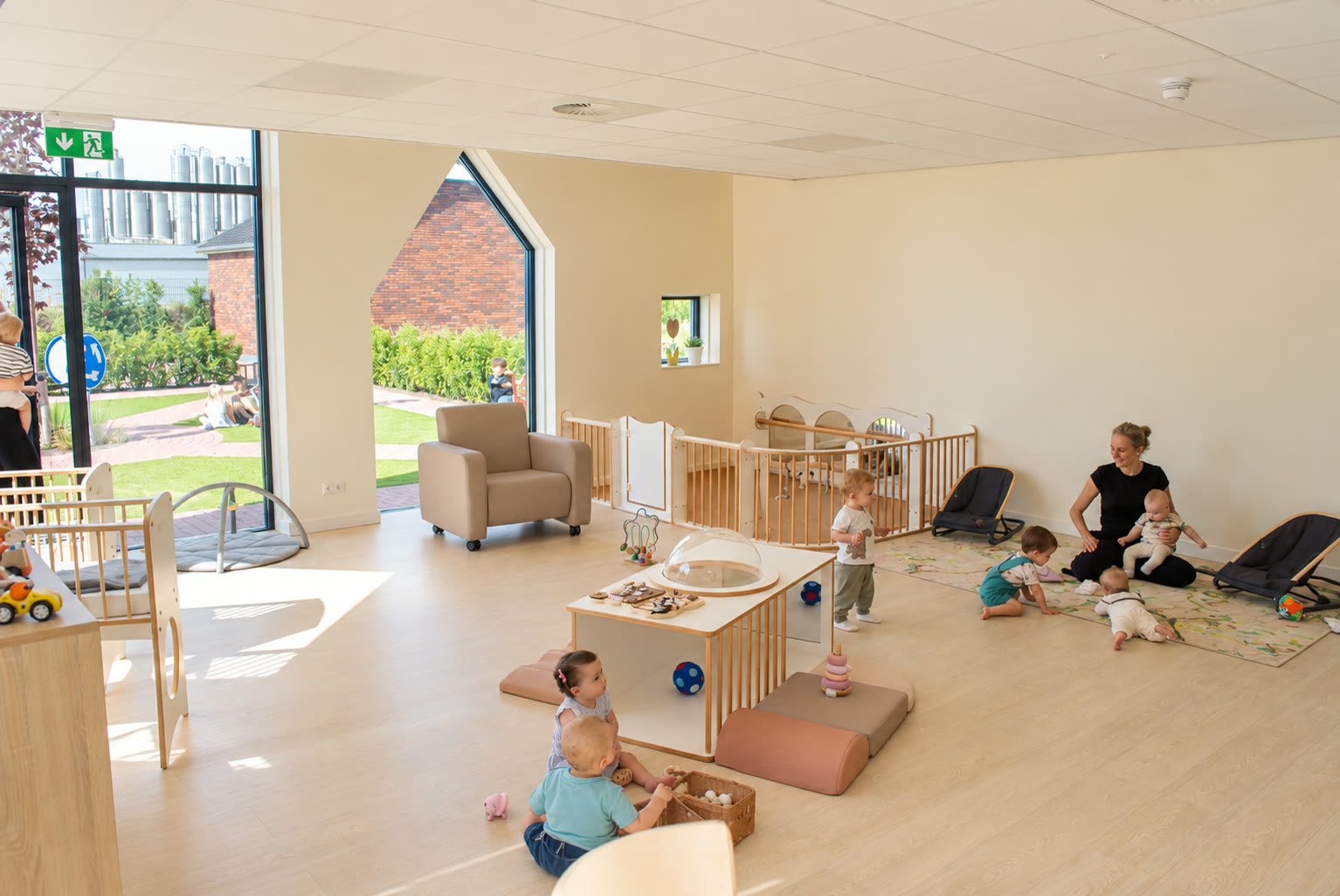 Pedagogisch medewerker speelt met baby's en peuters in een lichte groepsruimte
